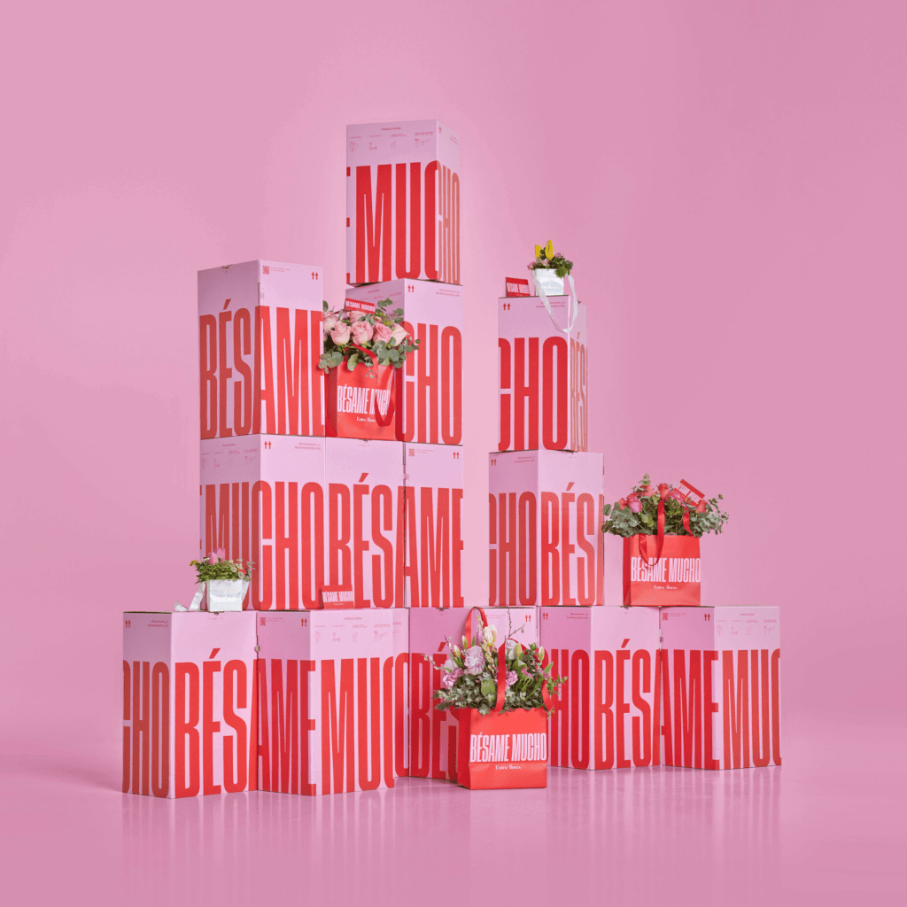 The packaging uses bright red with warm rose pink. And The bold typography: Bésame Mucho, Entre Flores. 